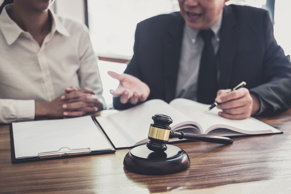 Two people reviewing legal documents at a table with a gavel in the foreground